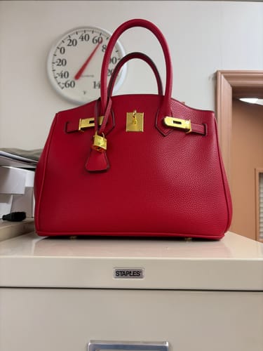 Customer's bright red Warkin Bag with gold hardware, sitting on top of a filing cabinet.