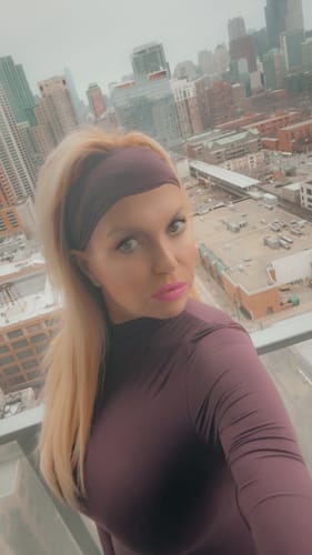 Customer on a balcony wearing the plum Naked Basic Headband with a matching top.