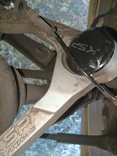 Close-up of a customer's black KSP Ball Joint Cover Replacement installed on a silver upper control arm.