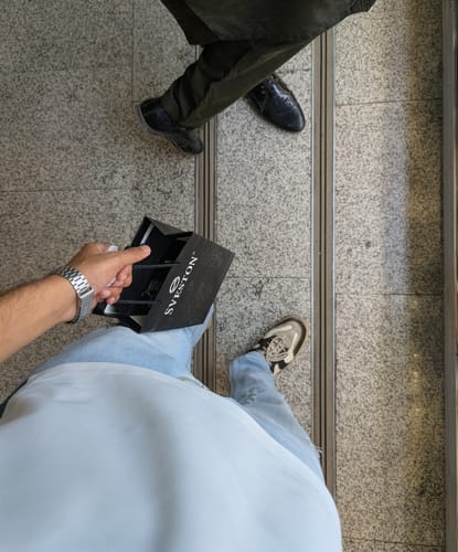 Customer's overhead view showing their new silver Elegant watch on their wrist while holding a Sveston bag.