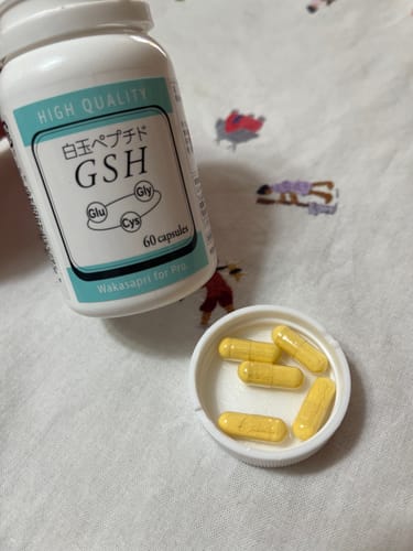 レビュー投稿者のワカサプリ 白玉ペプチドのボトルと、キャップに出された黄色いカプセル。