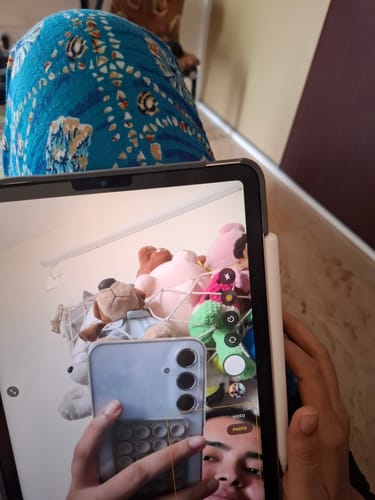 Reviewer taking a picture of their Samsung Galaxy A55 in a tablet's reflection to show the sleek, clear case.