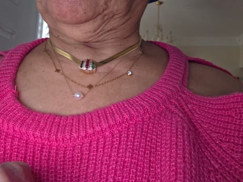 Close-up of a reviewer wearing the Clover Cutie Chain layered with a herringbone and a pearl necklace.