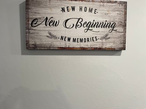 Customer's rustic 'New Home, New Beginning, New Memories' sign hanging on a light-colored wall.