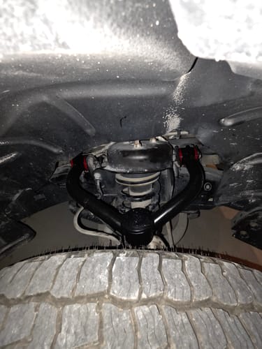 Customer's black Upper Control Arm Suspension Kit installed in the wheel well of a truck.