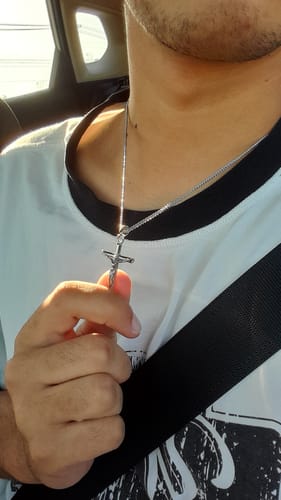 Cliente en un coche que lleva puesto el Colgante Cross Minimal y sostiene la cruz.