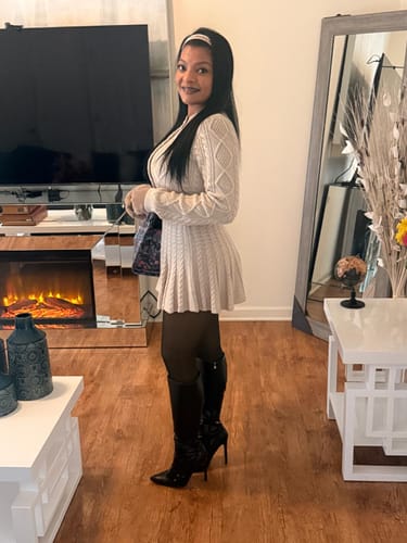 Reviewer standing in a living room wearing the Cable Knit Cropped Cardigan with a matching skirt and black boots.