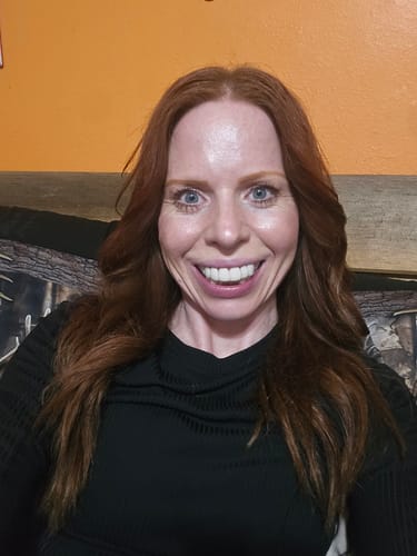 Reviewer smiling confidently, showing off her bright Pop On Veneers against an orange background.