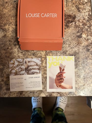 Customer's packaging for the Chelsea Octopus Ring, showing the orange box and included cards on a countertop.