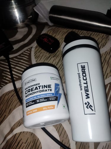 Customer's Wellcore Micronised Creatine Monohydrate tub and the included white steel shaker on a patterned surface.