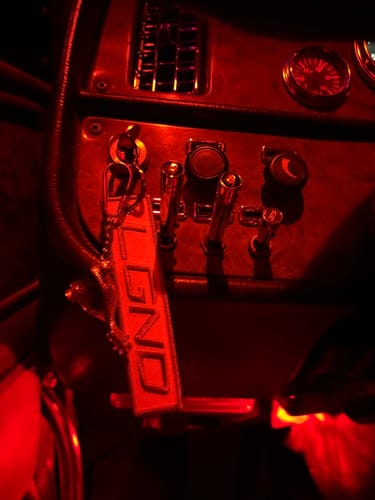 Customer's LGND87 jet tag accessory from the Mystery Box hanging inside a vehicle cab with distinct red lighting.