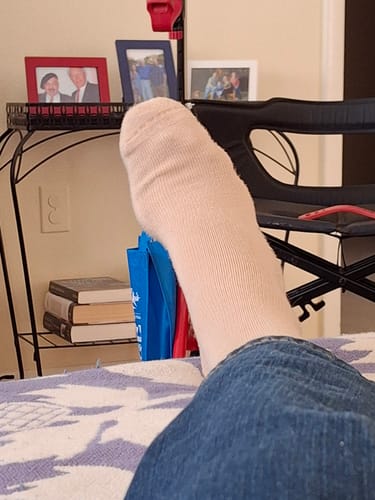Reviewer relaxing with their foot up, wearing a light-colored Performance Eucalyptus Compression Sock.