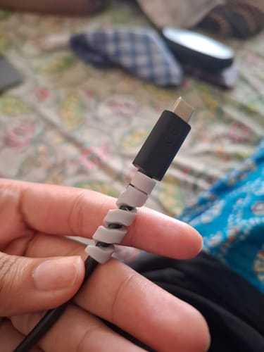 Customer's hand holding a black cable with the grey spiral Cable Protector wrapped near the end.