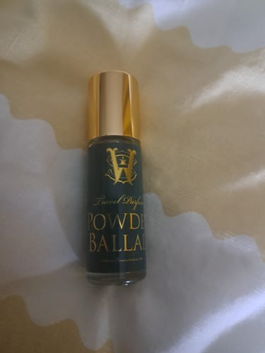 Customer's Powder Ballad perfume bottle, with a dark glass body and a gold cap.