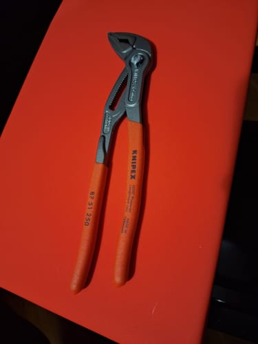 Customer's Knipex Cobra ES Water Pump Pliers with red handles laid out on a red surface.