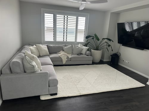 Customer's Mellow Mat Vector Lines 3D rug in a living room with a grey sofa and dark floors.