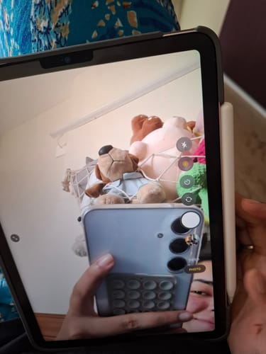 Reviewer showing a gray StickyPod with suction cups attached to the back of their smartphone.