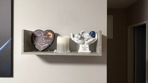 Ein Kunde zeigt das individuelle Schieferherz, das auf einem Regal neben einer Kerze in einer Wohnung ausgestellt ist.