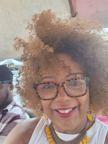 Customer smiling while wearing the curly, blonde Bahama Mama full wig.