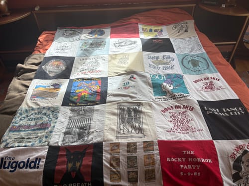Reviewer's colorful Premium T Shirt Quilt, made from many personal t-shirts, spread across a bed.