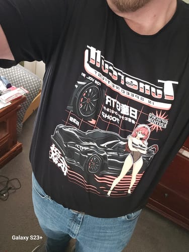 Customer wearing a black graphic t-shirt from their mystery box, featuring a pink and white anime and car design.