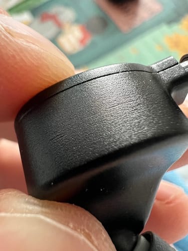 Close-up of a reviewer holding the textured black shell of a Symphonium Audio Helios headphone.