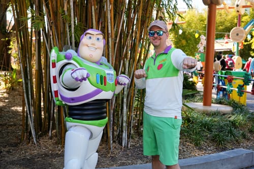 Customer wearing the green and white 'The Buzz' Quarter Zip, posing next to the Buzz Lightyear character.