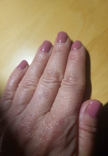 Kundenrezension: Nahaufnahme einer Hand, die die glänzenden, rosenholzfarbenen UV Gel Nagelfolien 'Rosewood Charm' trägt.