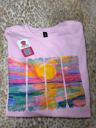 Reviewer's pink t-shirt with a vibrant, colorful sunset print made with the DTF Starter Bundle.