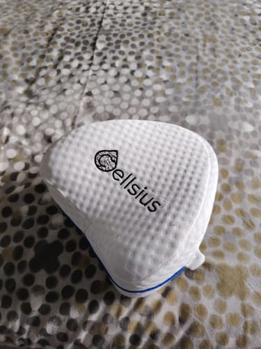 Un client montre le coussin orthopédique Cellsius, blanc et texturé, sur un lit.