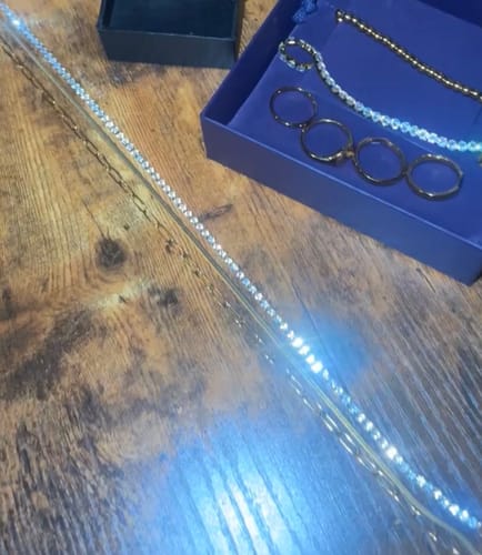 Customer's Chelsea Herringbone Necklace shown on a wooden table with other jewelry pieces.