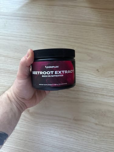 Customer holding a black tub of Complex Beetroot Extract.