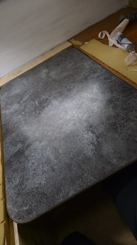 Nærbilde av anmelderens bord dekket med den grå, teksturerte Avellino betong kontaktplast.