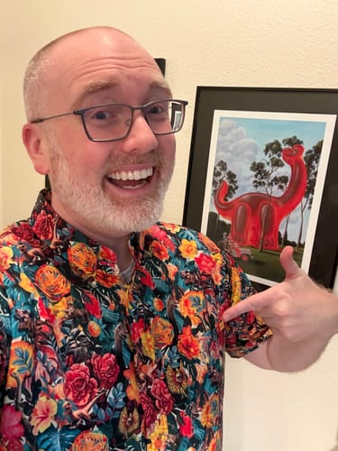 Reviewer smiling while wearing the colorful floral Jurassic Park 'Dinoflor' shirt.
