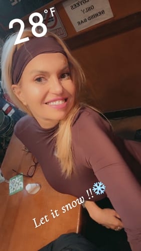 A smiling reviewer wearing a mauve long-sleeve top and matching headband.