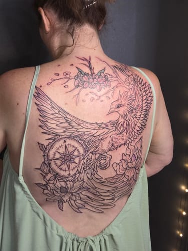 Customer's large, detailed back tattoo of a phoenix and compass healing with Alpha Tattoo Butter.