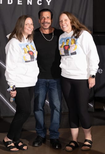 Reviewers wearing custom hoodies featuring their 'Turn Me Yellow' digital portrait while posing with a man.
