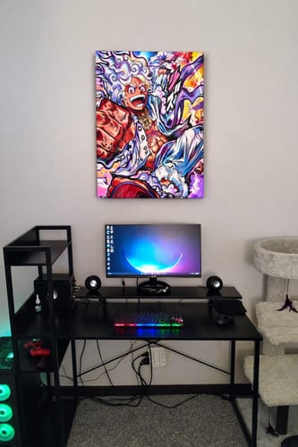 Customer's vibrant Luffy Gear 5 Wall Art hanging on the wall above a black computer desk and gaming setup.