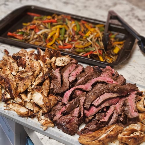 Customer's platter of fajitas featuring sliced Outside Skirt Steak cooked medium-rare, with chicken and peppers.