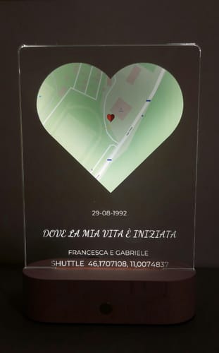 Ein Kunde zeigt die beleuchtete personalisierte Nachtleuchte mit einer herzförmigen Karte und Text auf dem Holzsockel.