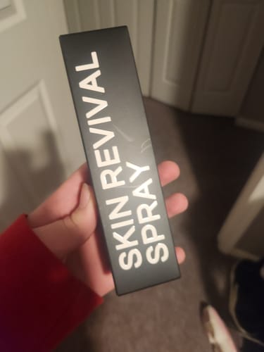 Customer holding the black box packaging for the Skin Revival Spray.