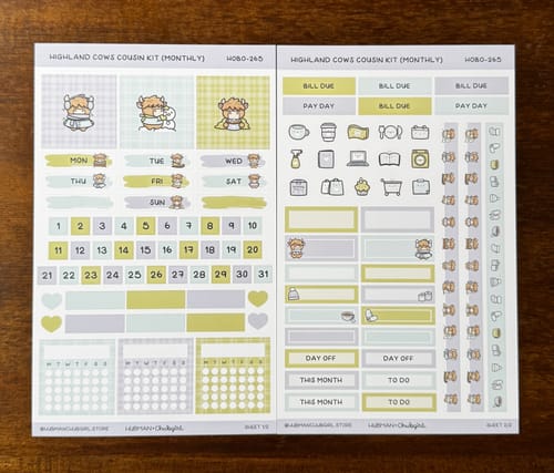 Reviewer displays the two sticker sheets from the Winter Highland Cows Hobonichi Cousin Monthly Kit.