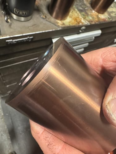 Close-up of a reviewer holding a piece of raw copper-colored metal, part of the ring making process.
