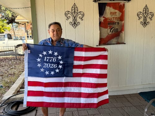 Reviewer holding the 1776 to 2026 Betsy Ross Flag open in front of their home.