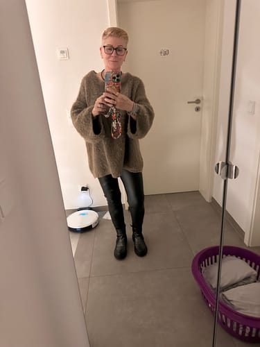 Kundin trägt den weichen, braunen Ultra-Soft Off-Shoulder Strickpullover mit lockerer Passform.