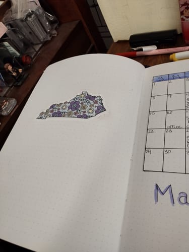 Reviewer's Kentucky Floral Sticker inside a bullet journal next to a hand-drawn calendar.