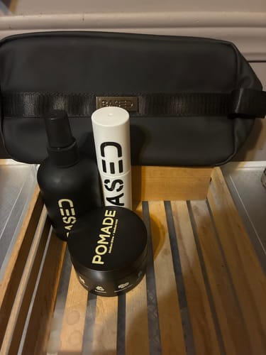 Reviewer's hair products including pomade, texture powder, and sea salt spray displayed with a black toiletry bag.