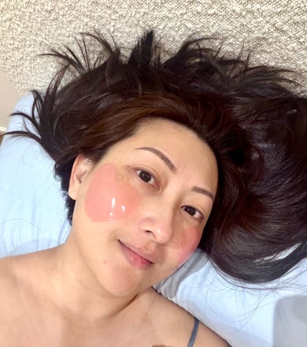 Reviewer relaxing with pink Hydrogel Patches applied to their cheeks.