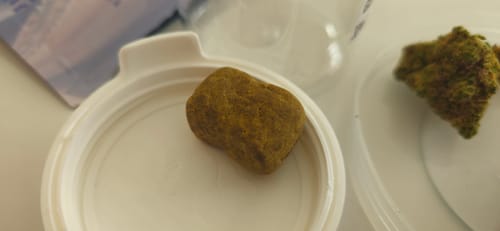 Close-up: Reviewer's golden-brown block of Golden Mousse resting on a white container lid.