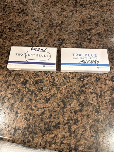Customer's boxes of Blue Cannatine™ and Just Blue, with 'ENERGY' and 'BRAIN' handwritten on them.
